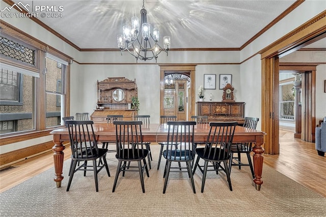 dining room with light hardwood / wood-style floors, a healthy amount of sunlight, a chandelier, and ornamental molding