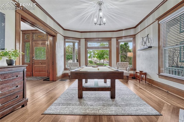 playroom with light wood-type flooring, an inviting chandelier, ornamental molding, and pool table