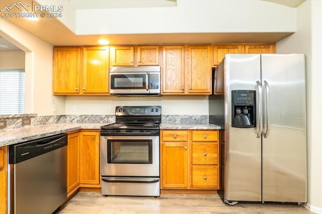 kitchen featuring light stone counters, stainless steel appliances, and light hardwood / wood-style flooring