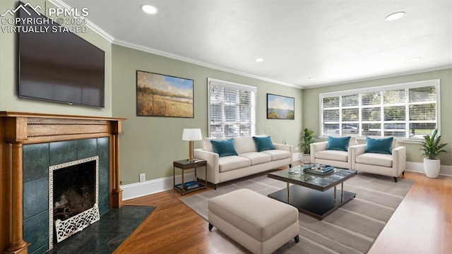 living room with crown molding, hardwood / wood-style floors, and a tile fireplace