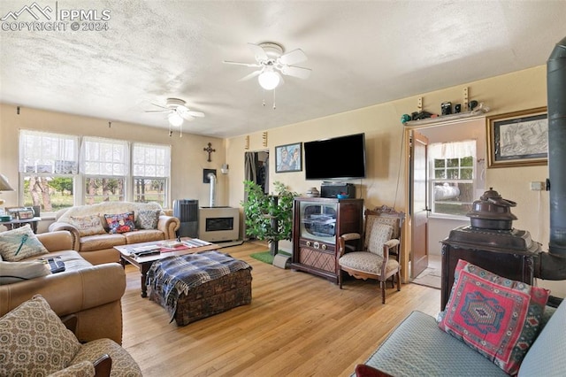 living room with a textured ceiling, light hardwood / wood-style flooring, and ceiling fan