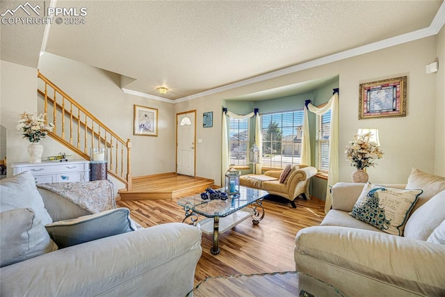 living room with a textured ceiling, crown molding, and light wood-type flooring