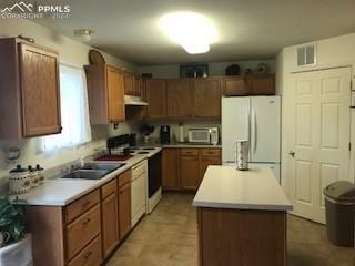 kitchen featuring sink, white appliances, light tile floors, and a kitchen island