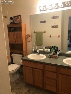 bathroom featuring dual bowl vanity and toilet