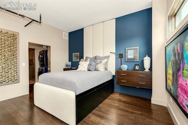 bedroom with a walk in closet, dark hardwood / wood-style floors, and a closet