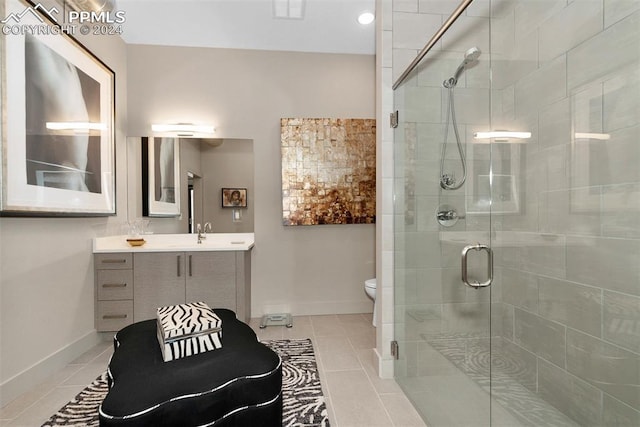 bathroom with tile patterned flooring, vanity, a shower with door, and toilet