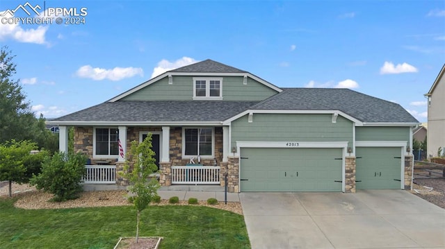 view of front of home featuring a garage, covered porch, and a front lawn