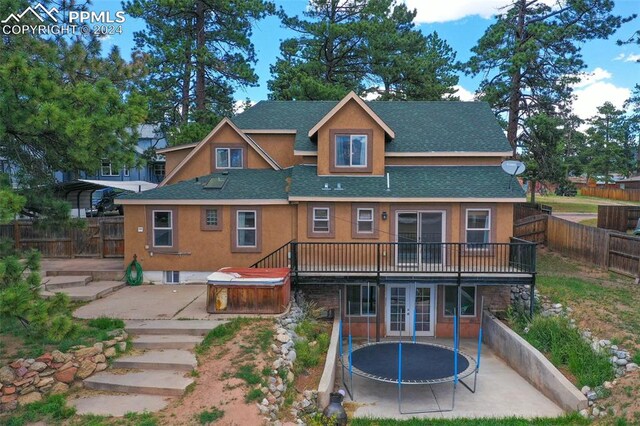 rear view of house featuring a deck, a patio, french doors, a trampoline, and a hot tub