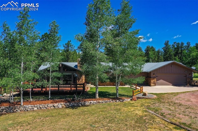 view of front of house with metal roof, an attached garage, driveway, stone siding, and a front lawn