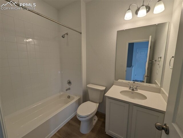 full bathroom featuring hardwood / wood-style floors, vanity, tiled shower / bath combo, and toilet