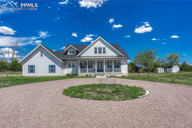 view of front of property with a storage shed, covered porch, and a front yard