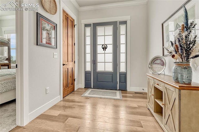 foyer entrance with ornamental molding and light wood-type flooring