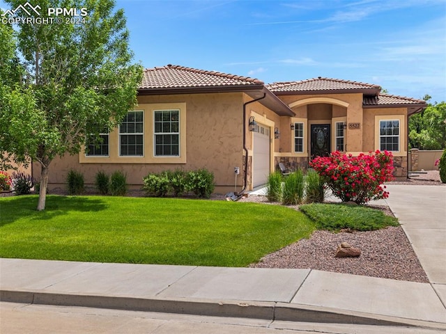 mediterranean / spanish-style home with a front yard and a garage