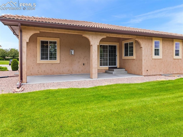 back of house featuring a lawn and a patio