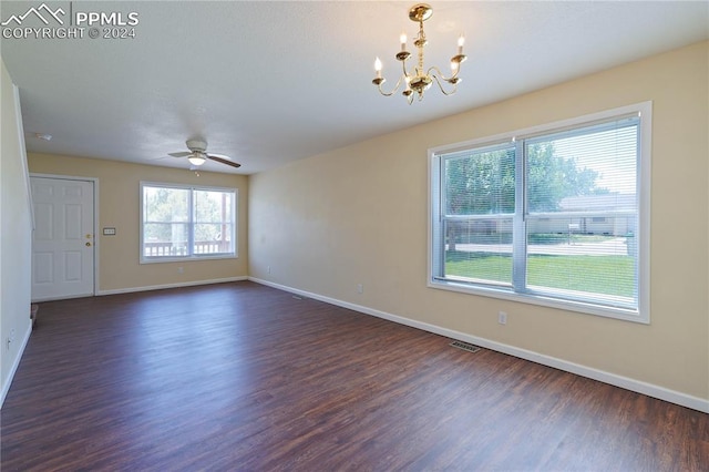 unfurnished room featuring plenty of natural light, dark wood-type flooring, and ceiling fan with notable chandelier