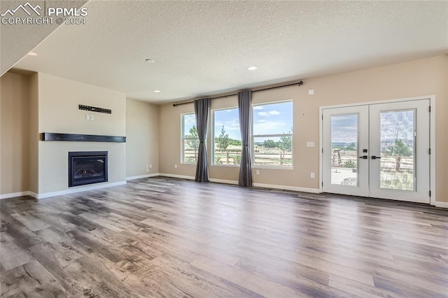 unfurnished living room featuring french doors, a textured ceiling, and hardwood / wood-style flooring