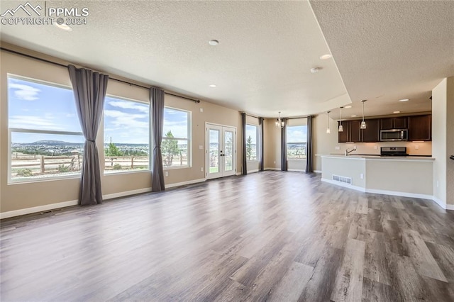 unfurnished living room featuring a textured ceiling, wood-type flooring, and french doors