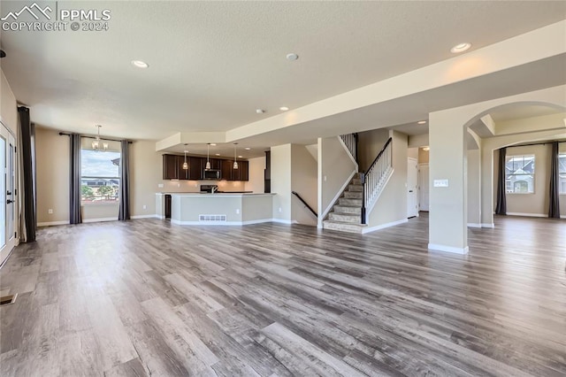 unfurnished living room featuring an inviting chandelier and hardwood / wood-style floors