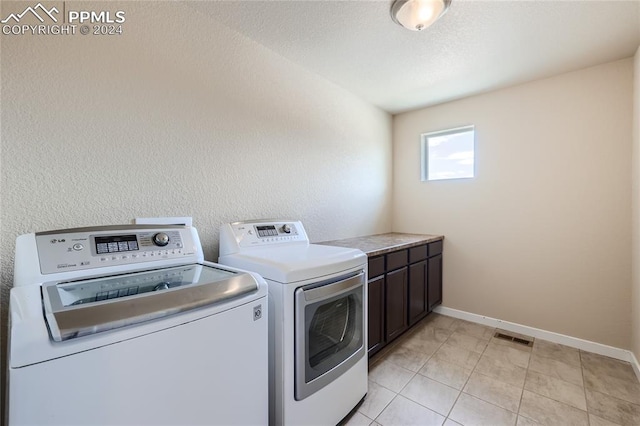 laundry room with cabinets, light tile patterned flooring, and separate washer and dryer