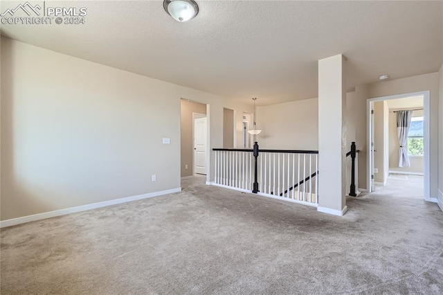 unfurnished room with light colored carpet and an inviting chandelier