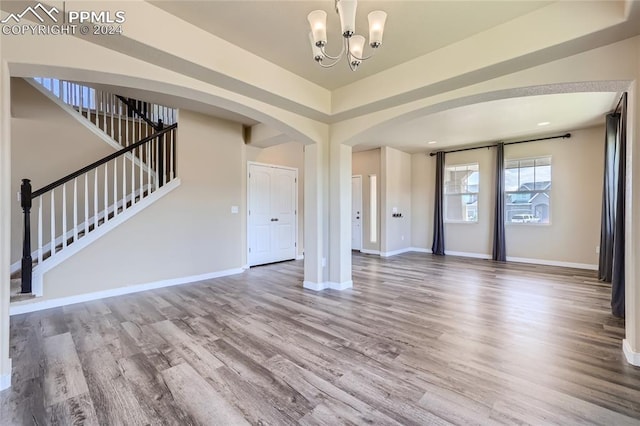 unfurnished living room with hardwood / wood-style flooring and a notable chandelier