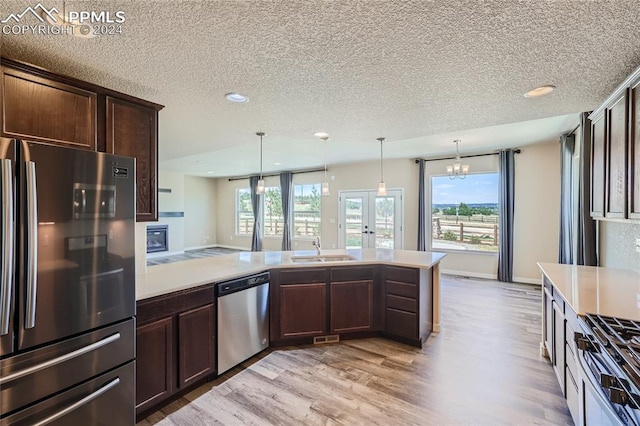 kitchen featuring a wealth of natural light, appliances with stainless steel finishes, an inviting chandelier, sink, and hanging light fixtures