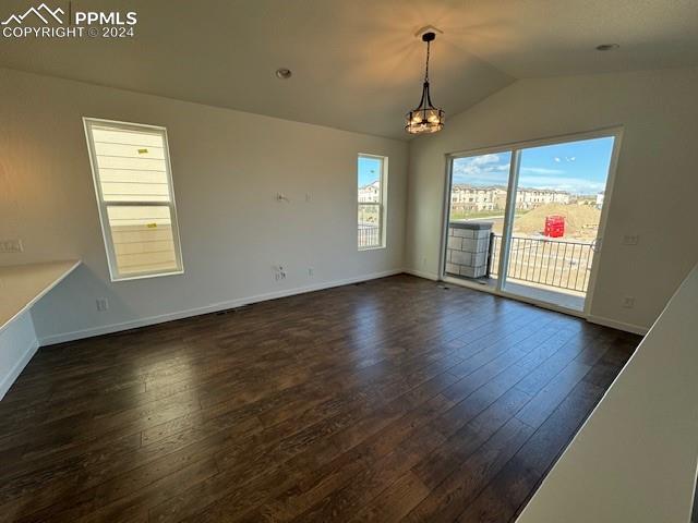 unfurnished room featuring vaulted ceiling, dark hardwood / wood-style floors, and a notable chandelier