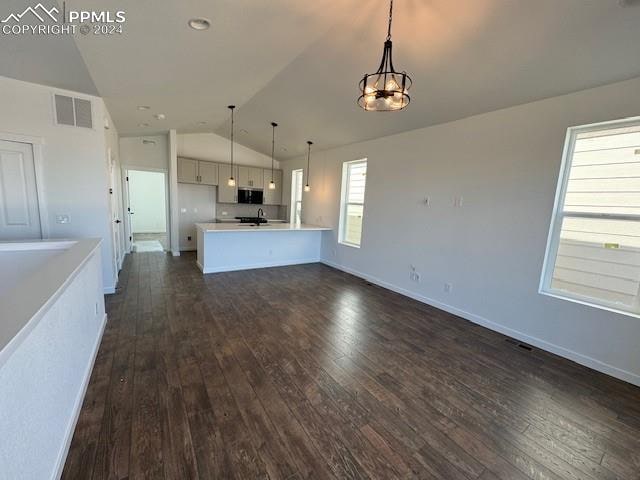 kitchen featuring dark wood-type flooring, hanging light fixtures, kitchen peninsula, and lofted ceiling