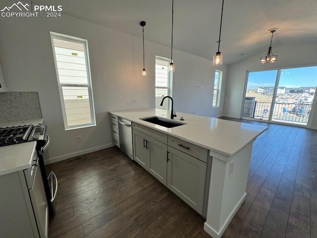 kitchen featuring appliances with stainless steel finishes, dark hardwood / wood-style flooring, vaulted ceiling, pendant lighting, and sink