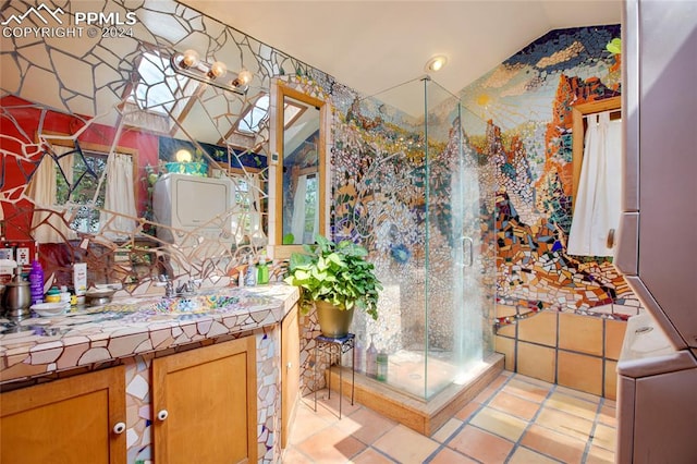 bathroom with a shower with shower door, vanity, tile patterned floors, and vaulted ceiling