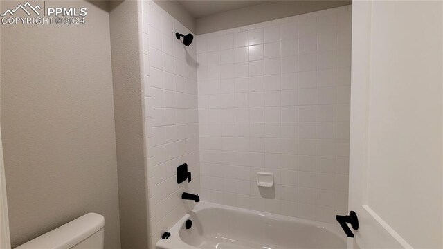 bathroom with toilet and tiled shower / bath