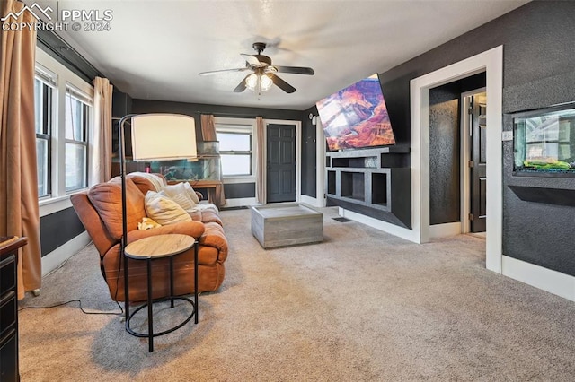 carpeted living room featuring built in shelves and ceiling fan