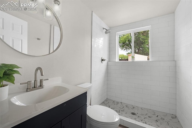 bathroom featuring vanity, toilet, and a tile shower