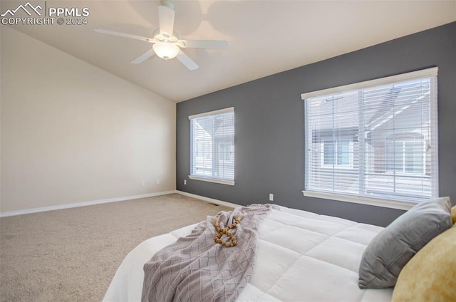 carpeted bedroom with ceiling fan, vaulted ceiling, and multiple windows