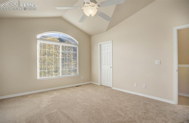 spare room featuring ceiling fan, light colored carpet, a healthy amount of sunlight, and vaulted ceiling