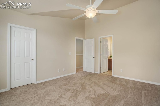 unfurnished bedroom featuring ensuite bathroom, light carpet, high vaulted ceiling, and ceiling fan