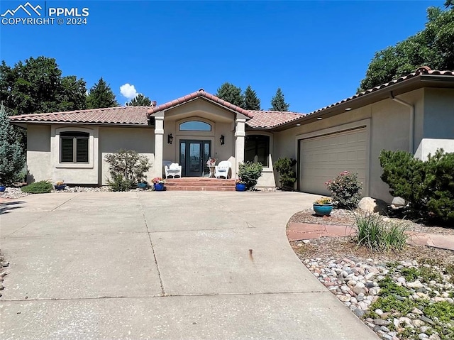 mediterranean / spanish-style home featuring a tiled roof, stucco siding, and french doors