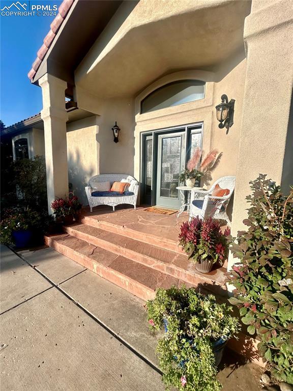 property entrance featuring stucco siding, a tiled roof, and a patio