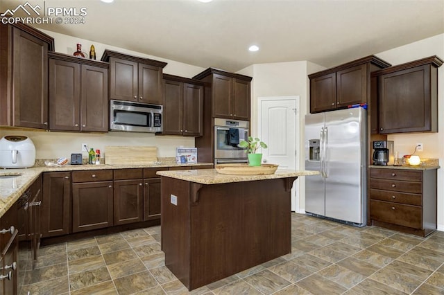 kitchen featuring a kitchen breakfast bar, dark brown cabinetry, and stainless steel appliances