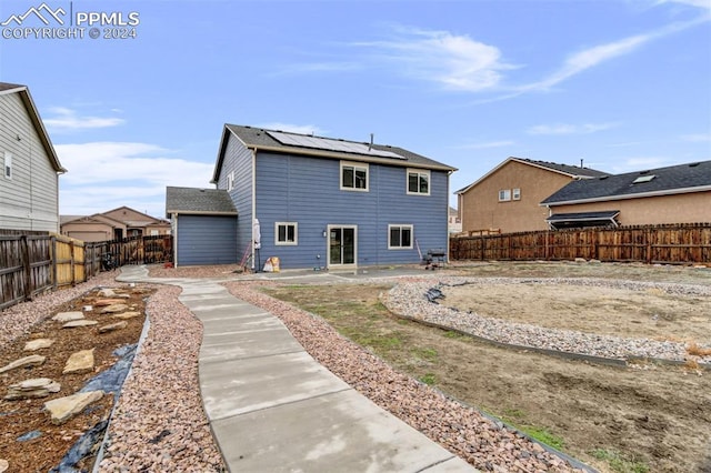 rear view of property featuring a patio and solar panels