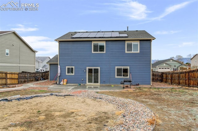 rear view of house with a patio area and solar panels