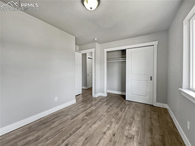 unfurnished bedroom with light wood-type flooring and a closet