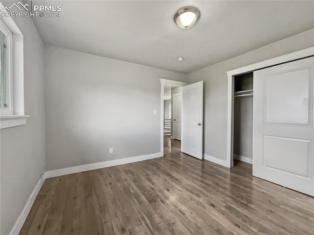 unfurnished bedroom with hardwood / wood-style flooring and a closet