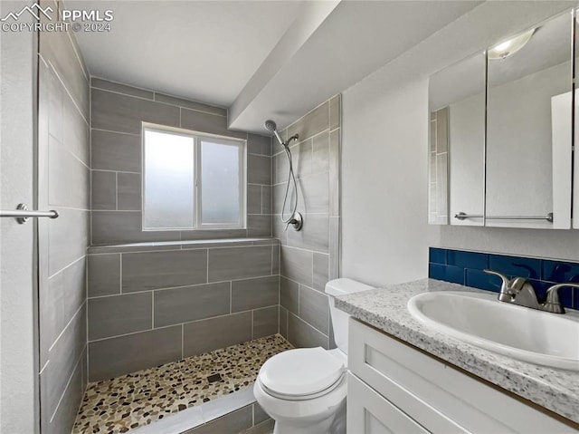 bathroom featuring vanity, toilet, and tiled shower