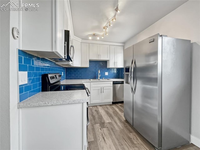 kitchen featuring white cabinetry, sink, backsplash, light hardwood / wood-style floors, and appliances with stainless steel finishes