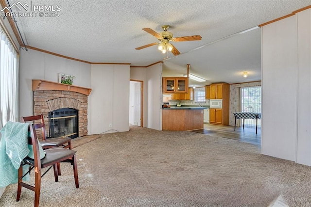 carpeted living room featuring a fireplace, a textured ceiling, ceiling fan, and ornamental molding