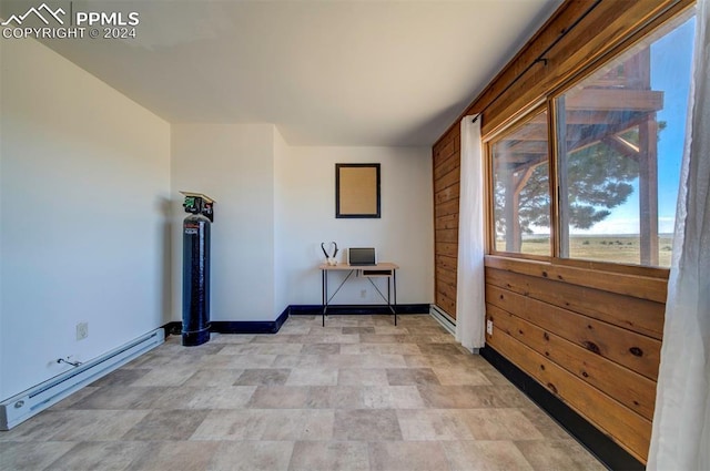 interior space with wood walls and a baseboard heating unit