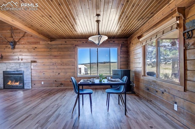 dining room featuring wooden walls, wood-type flooring, a fireplace, and wood ceiling