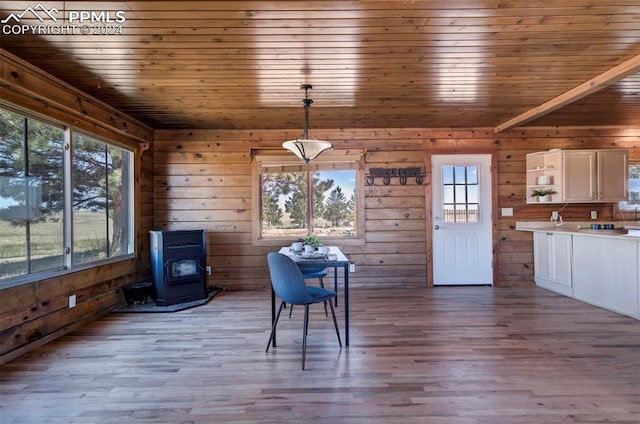 unfurnished dining area featuring wooden ceiling, a wood stove, a wealth of natural light, and light hardwood / wood-style flooring