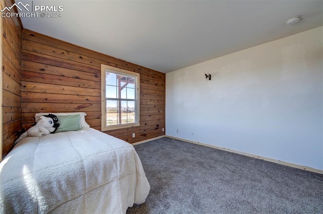 bedroom with dark colored carpet and wood walls